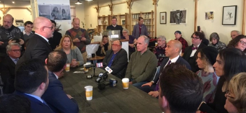 US Sen. Bob Casey (D-PA), seated in green sweater, and US Sen. Cory Booker (D-NJ), seated in coat and tie, listen to a questioner during their roundtable discussion of LGBT issues during the Trump administration.