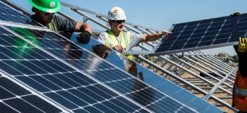 Workers install solar panels in a field. 