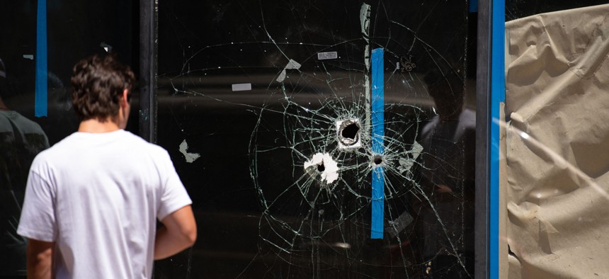 A pedestrian walks past bullet holes in the window of a storefront on South Street in Philadelphia on June 5, 2022.