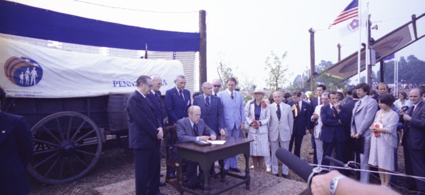 Gov. Milton Shapp (right of President Gerald Ford, seated) participates in the signing ceremony establishing Valley Forge State Park a National Historical Site.