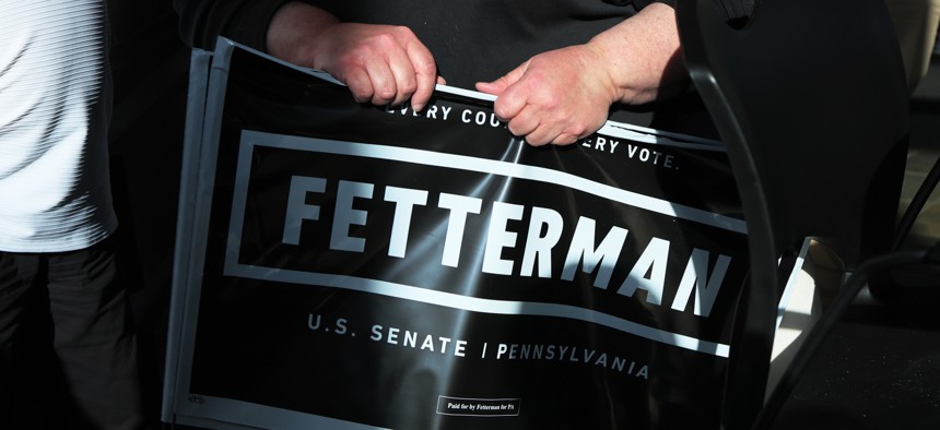 A supporter carries a campaign sign for Pennsylvania Lt. Gov. John Fetterman.