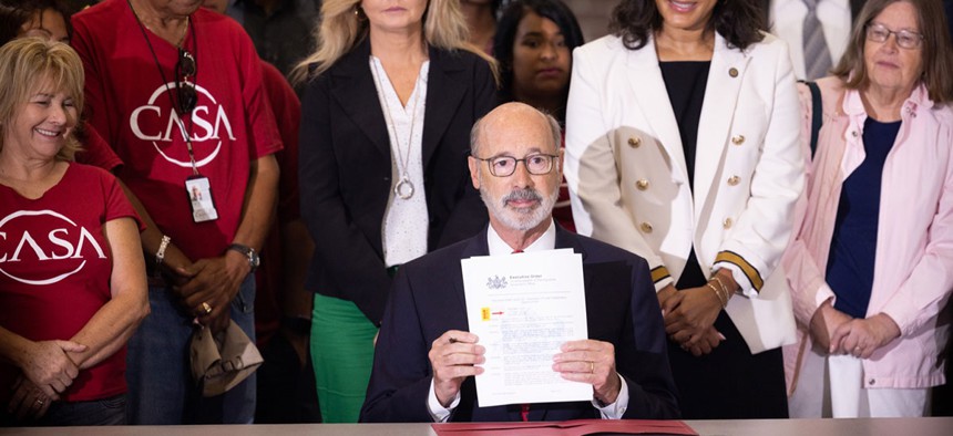 Gov. Tom Wolf shows an executive order he signed on Wednesday