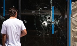 A pedestrian walks past bullet holes in the window of a storefront on South Street in Philadelphia, Pennsylvania, on June 5, 2022.