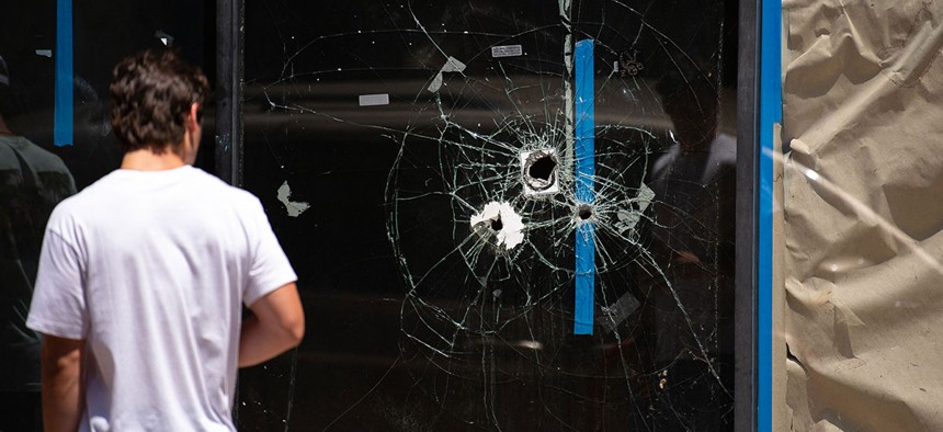 A pedestrian walks past bullet holes in the window of a storefront on South Street in Philadelphia, Pennsylvania, on June 5, 2022.