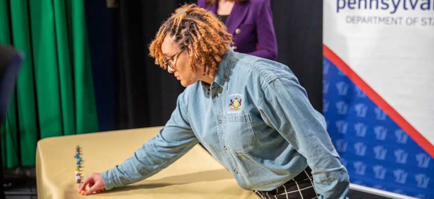 A Department of State employee places a 10-sided die on the table during the department’s dice rolling event. 