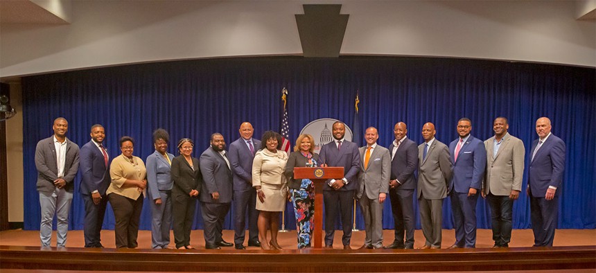 From left to right: Reggie Guy, Rep. Amen Brown, Rep. Darisha K. Parker, Rep. Regina Young, Rep. Donna Bullock, Rep. Jordan Harris, Auditor General Tim DeFoor, Leader Rep. Joanna McClinton, Marcia Perry Dix, David Dix, Nicholas Bertram, Sulaiman Rahman, Rep. Stephen Kinsey, Lt. Governor Austin Davis, Chuck Sanders, Gene Barr.