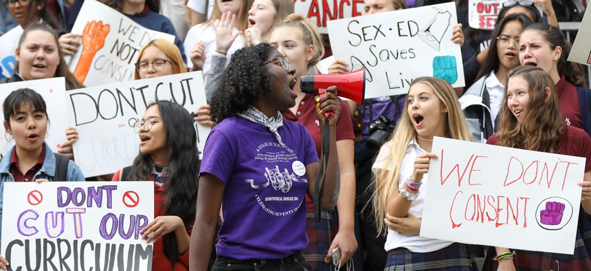 A woman uses a megaphone to lead the students of Notre Dame High School, an all-girl's Catholic school in protest of the province's repeal of the sex-ed curriculum and replacement of it with an outdated version.