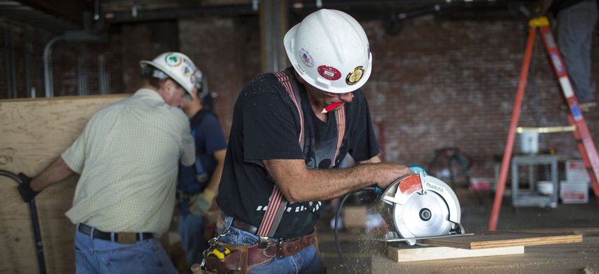 A carpenter cuts a piece of plywood for a floor covering.