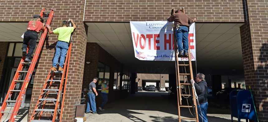 Luzerne County employees raise a banner outside of the elections bureau in Wilkes-Barre in October 2020.