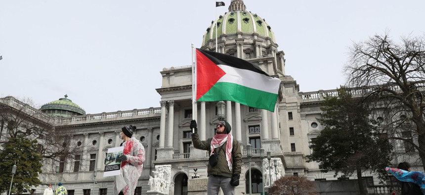 A protester holds a Palestinian flag during the Healthcare Workers for Palestine Rally on the steps of the Pennsylvania State Capitol.