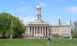 Students walk by Old Main at Pennsylvania State University.